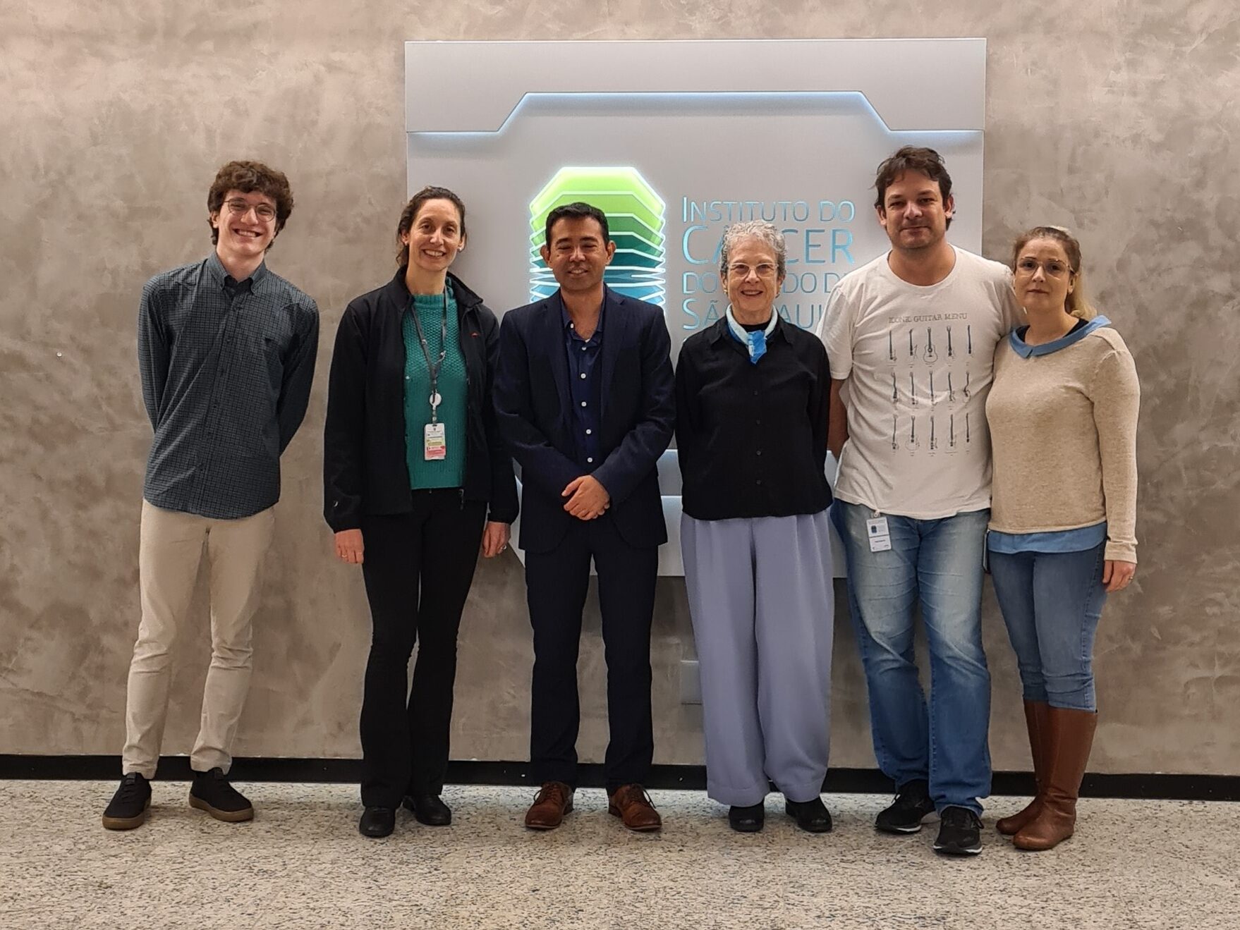 Un grupo de seis personas, incluido el orador Gabriel Sawakuchi, posan frente a un panel con el logo del ICESP.