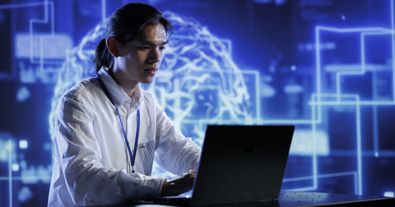 Foto de um homem asiático de camisa branca usando um computador.